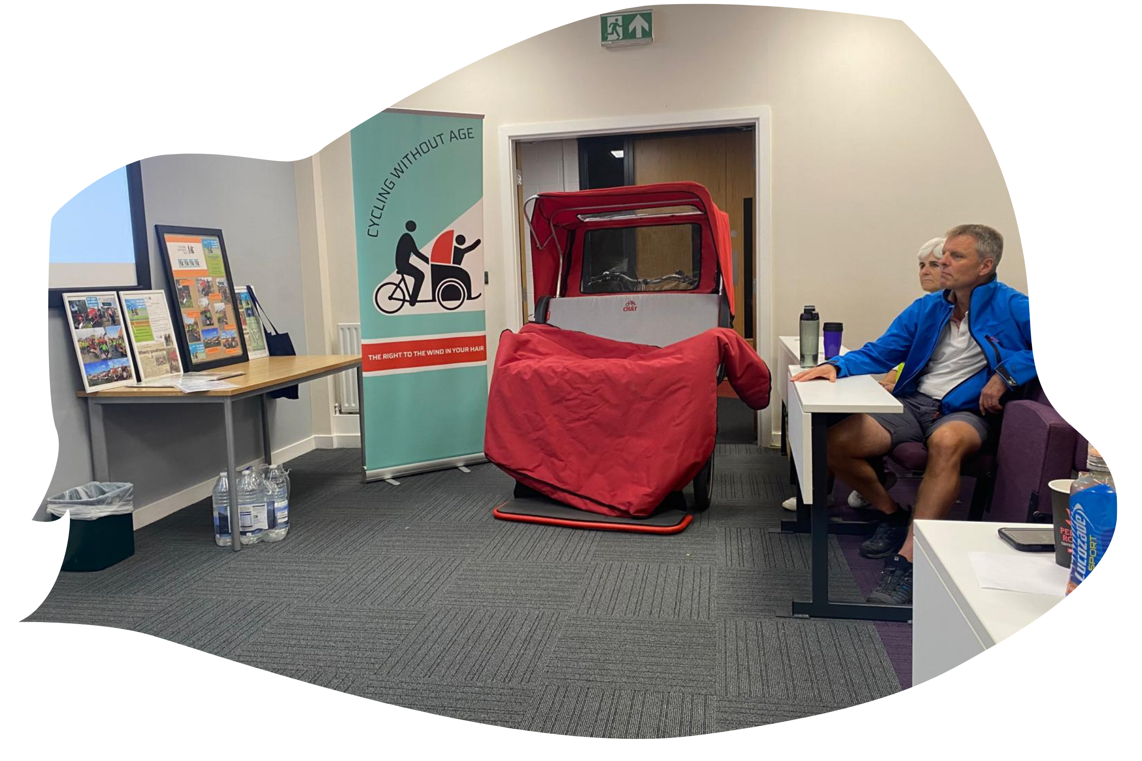 A trishaw and conference banner sit inside a conference room.